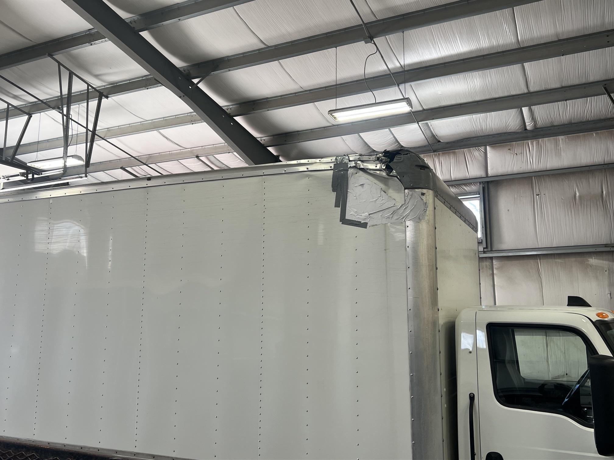 White box truck inside the Street Werx shop showing damaged upper corner cap
