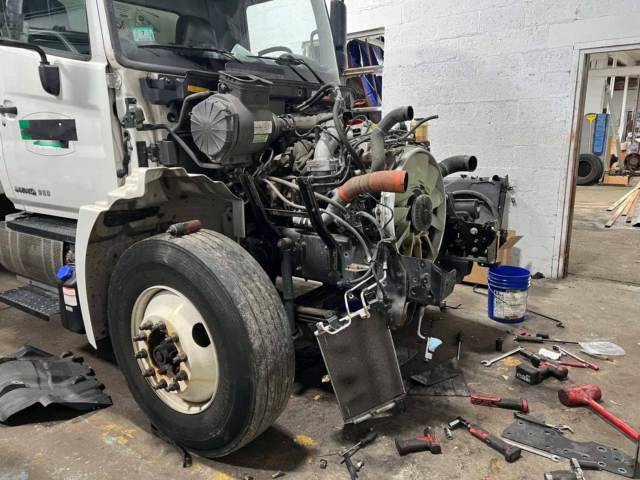 Commercial truck with hood up — diesel engine bay exposed mid-repair